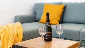A bottle of Bonaventure Cava wine on a wooden table with two glasses, a yellow throw blanket, and a grey sofa in the background. - Holiday Home 'Casa Cerro Del Aguila' with Mountain Views, Wi-Fi and Air Conditioning (CERROS DEL AGUILA)
