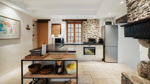 Een moderne keuken met een centraal kookeiland, inbouwapparatuur en een accentmuur van steen.