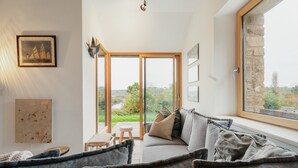 Een moderne woonkamer met een bank, een bijzettafeltje en uitzicht door een glazen deur.
