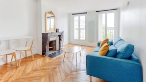 Ein Wohnzimmer mit Kamin, einem blauen Sofa und einem weißen Tisch.