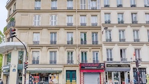 Ein mehrstöckiges Gebäude mit einem McDonald's Restaurant im Erdgeschoss, einem Restaurant mit roter Markise und einer Bäckerei und Konditorei auf der rechten Seite.