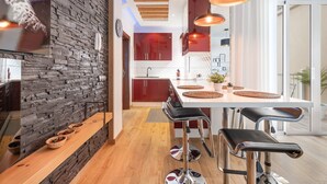 Una cocina moderna con pared de piedra, encimera de madera y taburetes de bar.