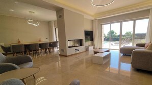 Ein modernes Wohnzimmer mit Fernseher, Sitzgruppe und Essbereich.