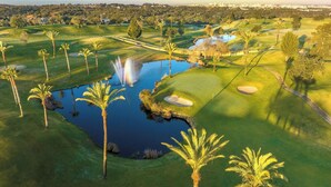 Ein Golfplatz mit Teich, Palmen und Wasserspielen.
