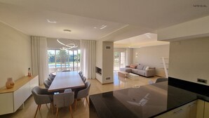 Ein modernes Wohnzimmer mit einer Couch, einem Essbereich mit Tisch und Stühlen sowie einer Küche mit schwarzem Arbeitsplatz.