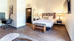 A modern hotel room with a bed, bedside tables, a desk, and a chair.