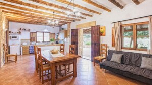 A rustic interior with exposed wooden beams, a dining area, a sofa, and a kitchen. - Villa 'Sa Cova' with Private Pool, Wi-Fi and Air Conditioning (Illes Balears)