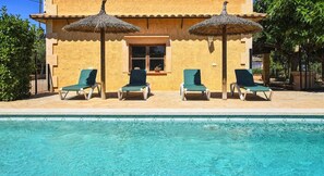 A pool with four lounge chairs and two thatched umbrellas. - Villa 'Sa Cova' with Private Pool, Wi-Fi and Air Conditioning (Illes Balears)