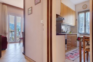 Keittiössä on puiset kaapit, ruokailutilassa punainen sohva ja suurista liukuovista avautuu näkymä ulos.