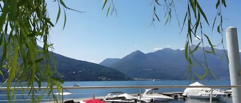 Una marina con barcos amarrados, una cadena montañosa al fondo y un cielo despejado.