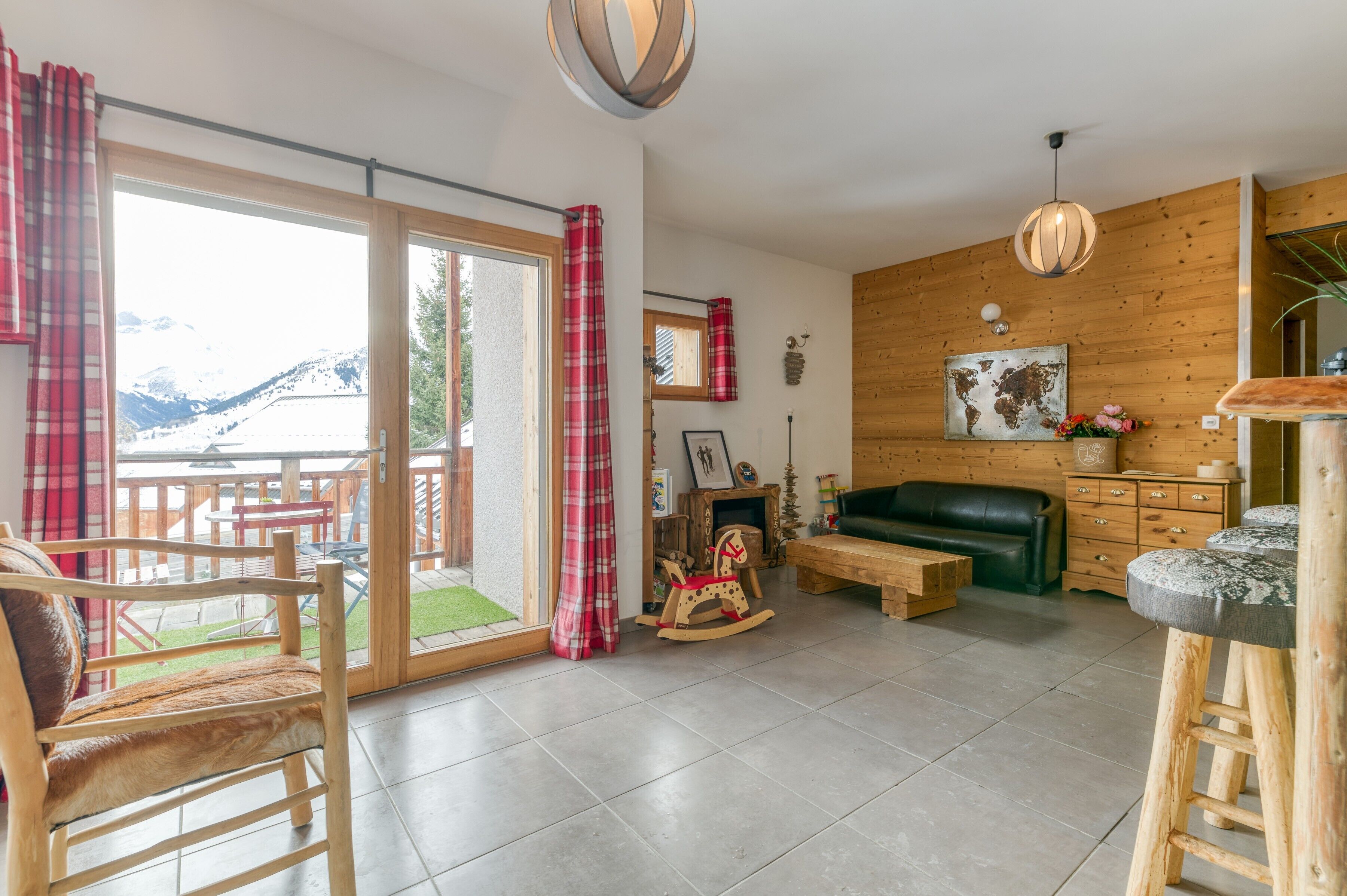 Un vaste espace de vie doté d’un plancher en bois, d’un canapé vert, d’un cheval à bascule, d’un banc en bois et d’un tabouret de bar.