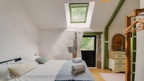 Une chambre avec un puits de lumière, un lit avec des serviettes, une commode et un miroir.