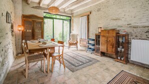 Une salle à manger rustique avec une table en bois, des chaises, un lustre et un buffet.