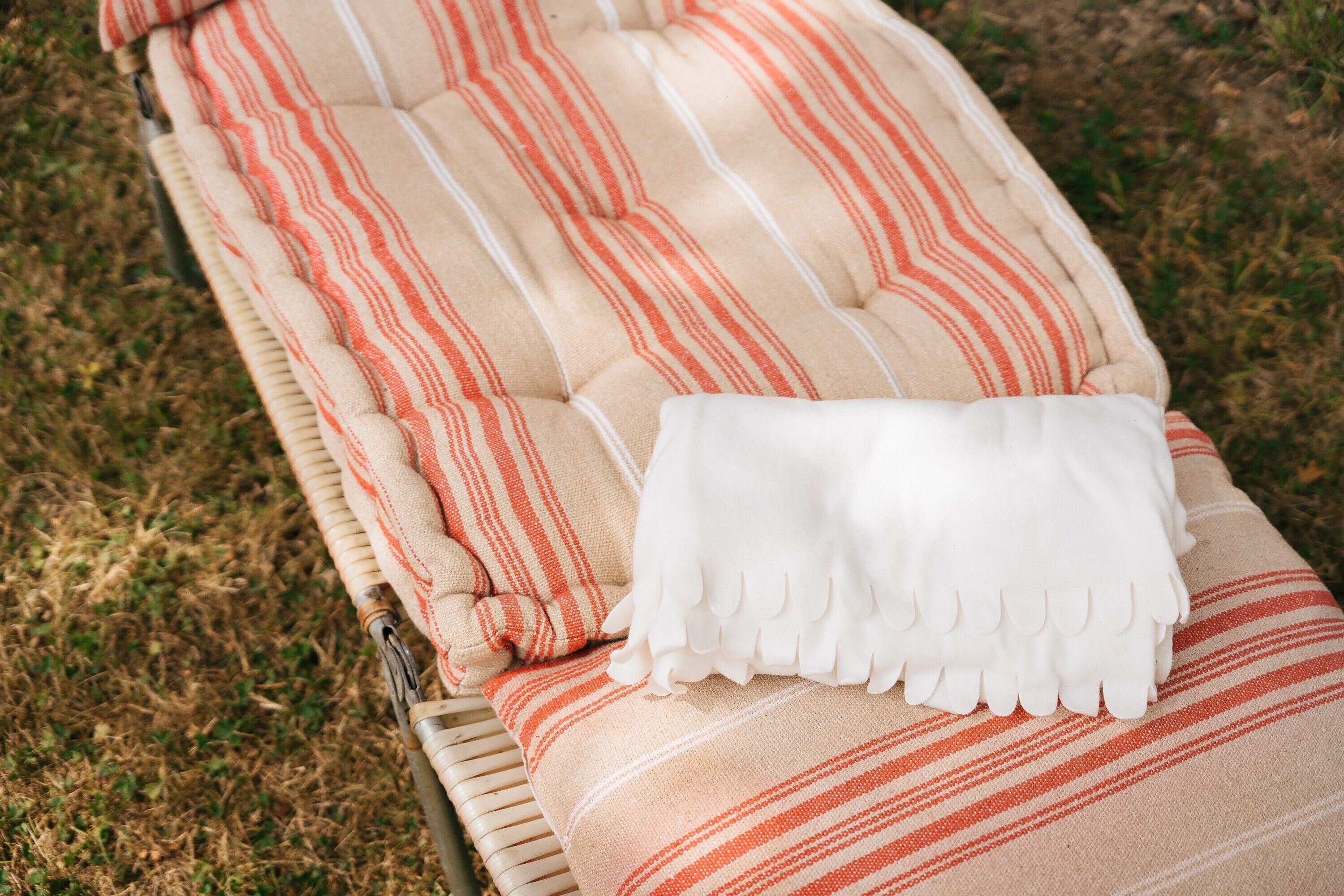 Una silla de descanso a rayas con un plaid blanco.