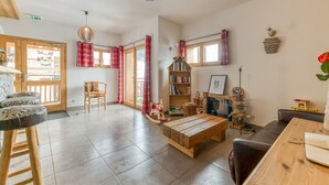 A spacious living area with a wooden table, a rocking chair, a bookshelf, and a fireplace.