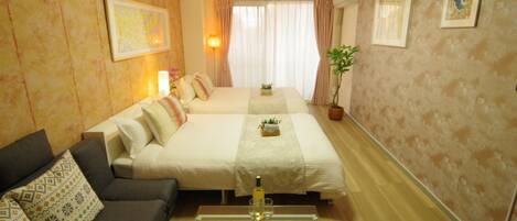 A hotel room with a bed, a sofa, a dining table with plates and cutlery, and a potted plant.