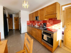 A modern kitchen with wooden cabinets, a stainless steel refrigerator, a microwave, and a coffee maker.