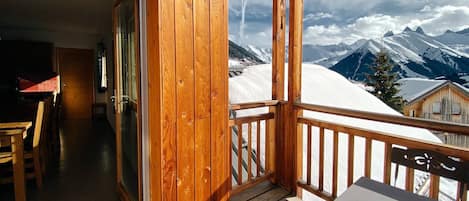 Un balcón de madera con vistas a montañas nevadas.