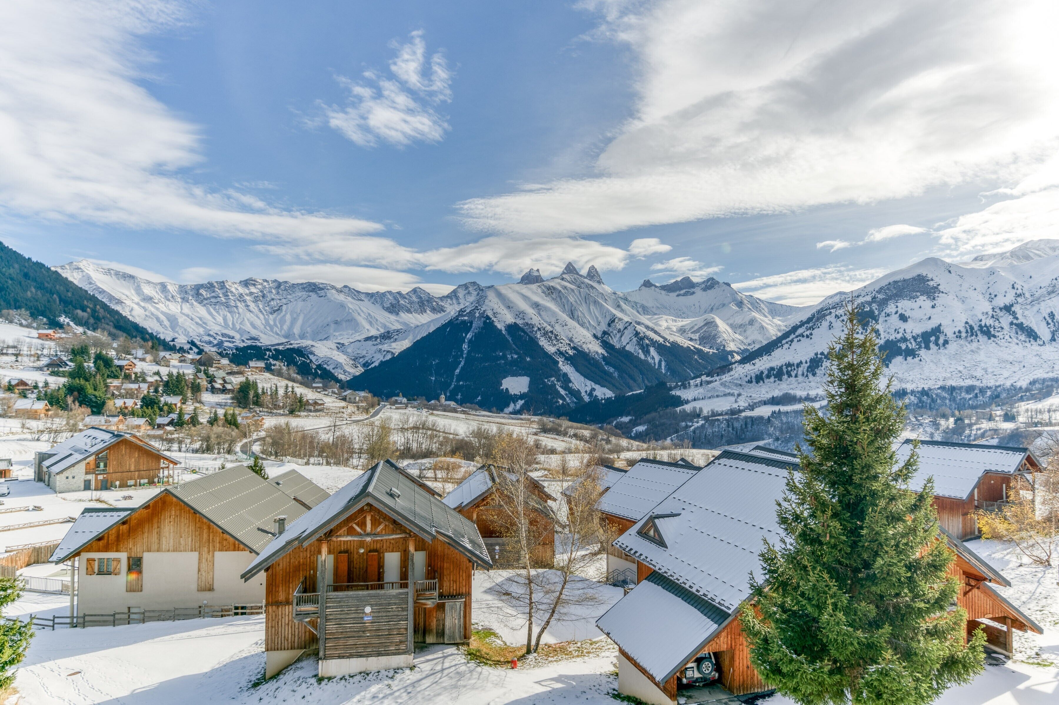 Ein verschneites Bergdorf mit Holzhäusern und Blick auf die umliegenden Gipfel.