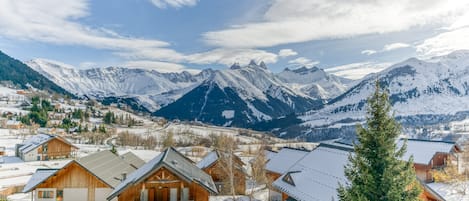 A snow-covered mountain village with wooden cabins and a view of the surrounding peaks.