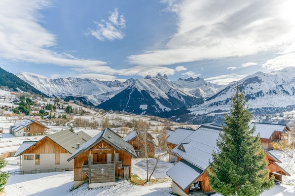 A snow-covered mountain village with wooden cabins and a view of the surrounding peaks.