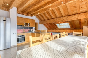 Et moderne køkken med træbjælker, et spiseområde med en stor seng og et ovenlys.