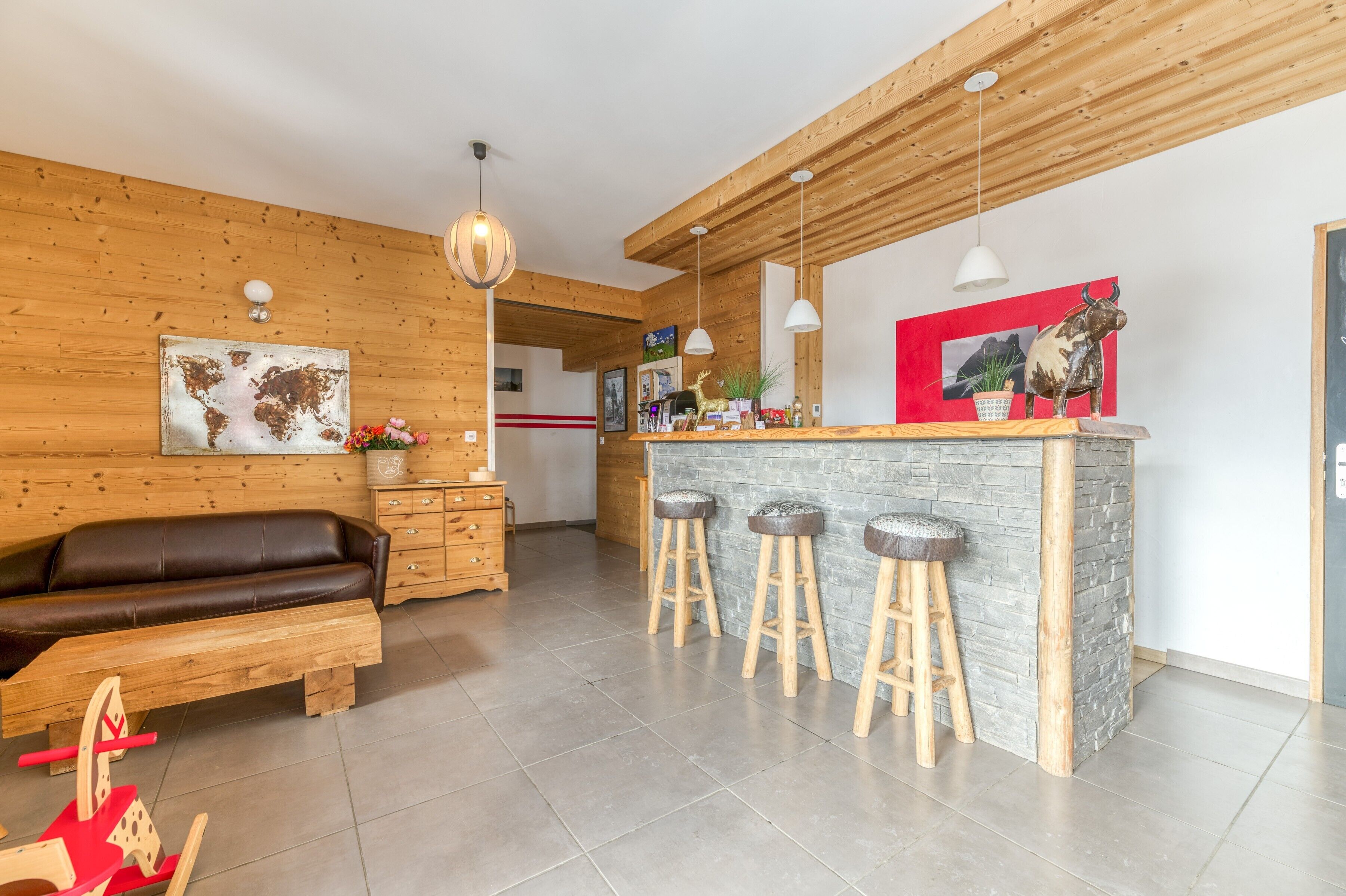 Une cuisine moderne avec un bar en bois, des tabourets et un coin salon comprenant un canapé et une table en bois.