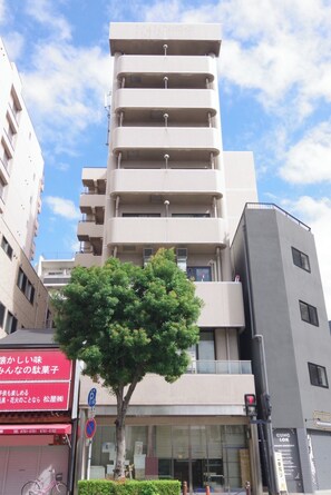 A multi-story building with balconies, a tree in front, and a sign with Japanese text. - 403 6 minutes walk from Nihonbashi Station Withi - 403 / Osaka Ōsaka (Osaka)