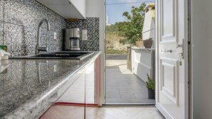 Een moderne keuken met een granieten aanrecht, een koffiezetapparaat en uitzicht op buiten.