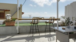 Een terras met twee stoelen, een tafel en een plant in pot.