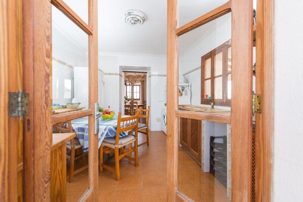 Une cuisine avec un coin repas, des meubles de rangement en bois et une fenêtre.
