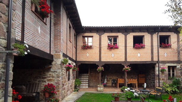 A courtyard with a stone building, potted plants, and outdoor seating.