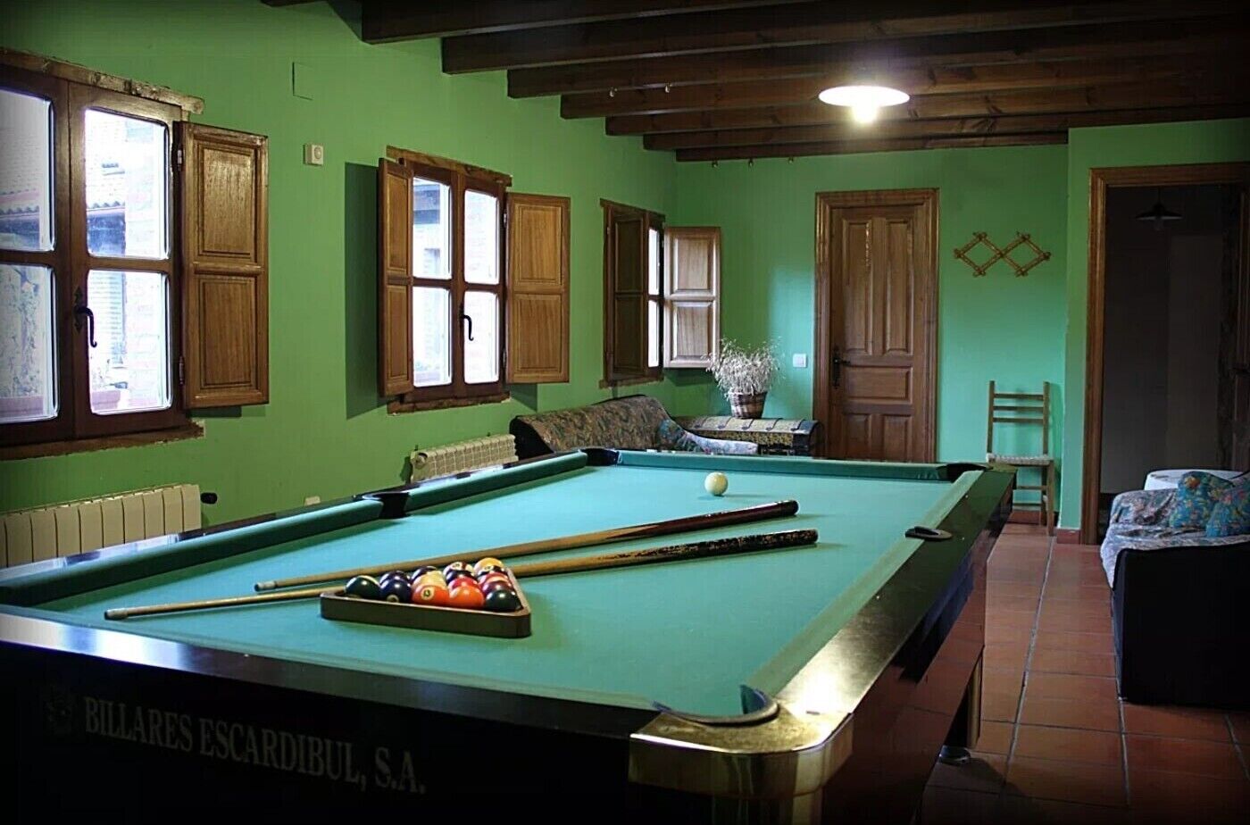 Une table de billard avec des billes, des meubles en bois et un radiateur.