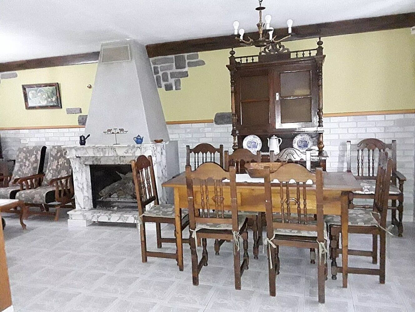 A dining area with a fireplace, wooden chairs, a table, and a decorative cabinet.
