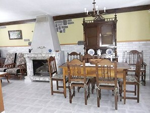 A dining area with a fireplace, wooden chairs, a table, and a decorative cabinet. - Country House 'Entrepeñas' with Mountain View, Shared Terrace and Wi-Fi (Mudá)