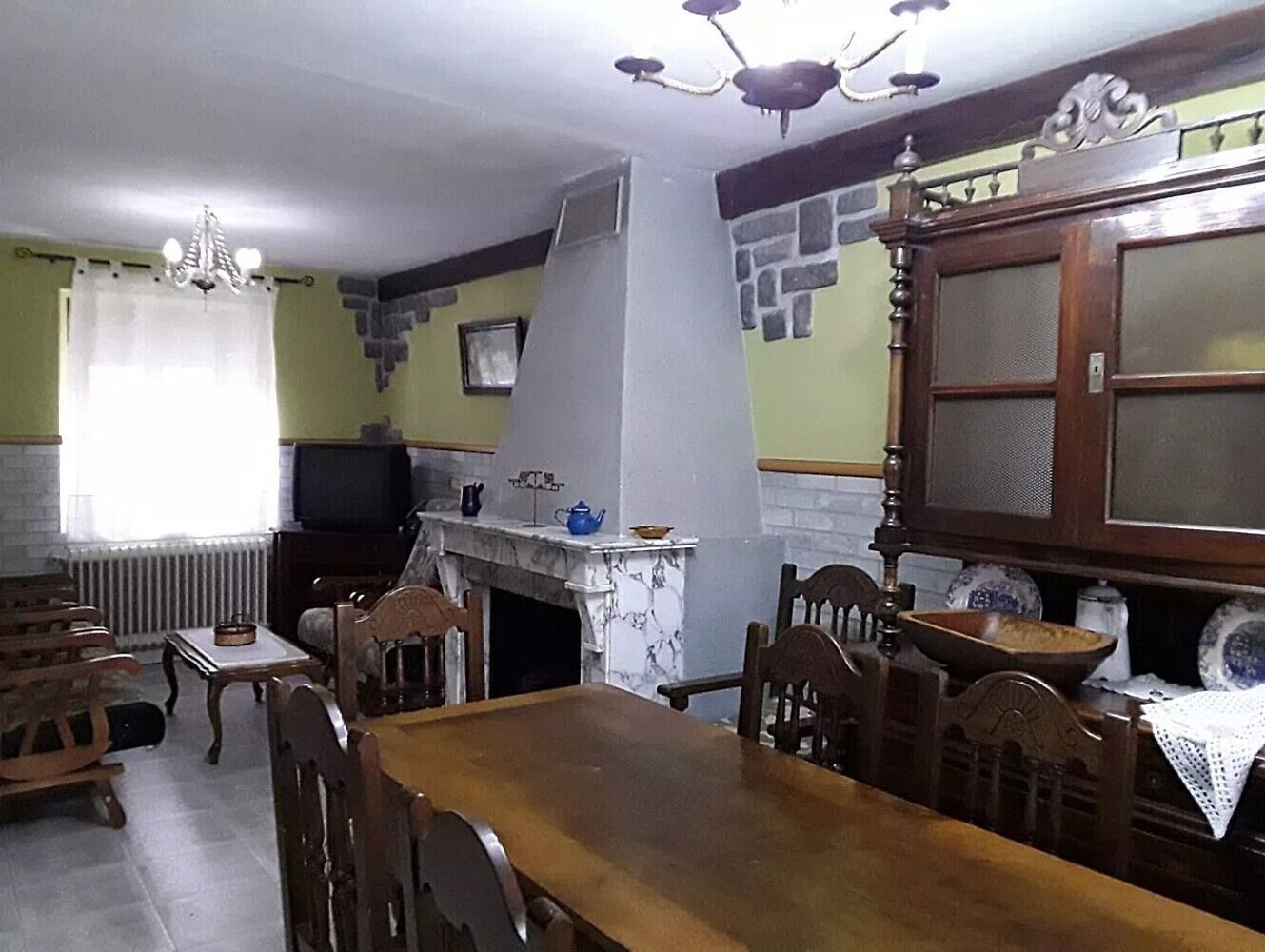 Un coin repas avec une table et des chaises en bois, une cheminée et un téléviseur en arrière-plan.