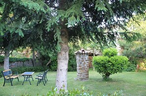 A garden with a stone structure, two benches, and a table. - Country House 'Entrepeñas' with Mountain View, Shared Terrace and Wi-Fi (Mudá)