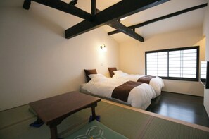 Makuuhuone, jossa on sänky, yöpöytä, ikkuna ja katto, jossa on näkyvillä olevat kattopalkit.