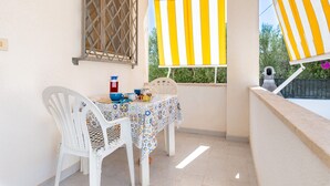 Ein Balkon mit Tisch, Stühlen und einem Streifen-Markisen.