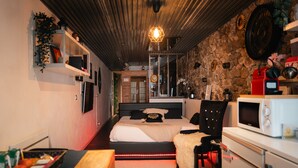 A bedroom with a bed, bedside table, and a microwave. - Apartment 'Sweet Loft Grenoble' with Wi-Fi and Air Conditioning (Grenoble)