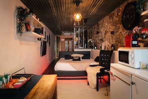 A bedroom with a bed, bedside table, and a microwave.