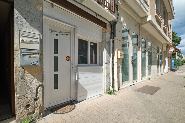 A building with a closed white door, a mailbox, and a no parking sign.