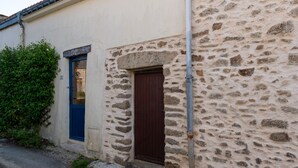 Un bâtiment en pierre avec une porte bleue et une porte marron, une petite fenêtre et un tuyau en métal.
