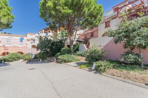 Rua residencial com casas, árvores e céu claro.
