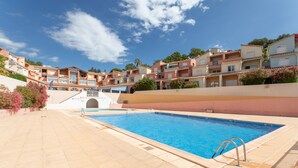 A swimming pool with a clear blue water, surrounded by a tiled deck, and adjacent to a multi-story building with balconies. - Apartment 'T2 Meublé Aux Aloès' with Mountain View, Shared Pool and Private Terrace (Cerbère)