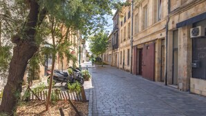 A cobblestone street lined with historic buildings, trees, and parked scooters. - Dari Apartment – Elegant Getaway in the Heart of Bordeaux (Bordeaux)