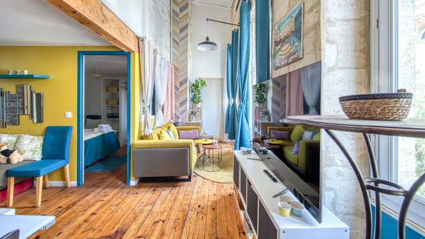 A cozy living room with a sofa, chairs, a table, and a TV. - Dari Apartment – Elegant Getaway in the Heart of Bordeaux (Bordeaux)