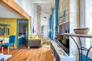 A cozy living room with a sofa, chairs, a table, and a TV.