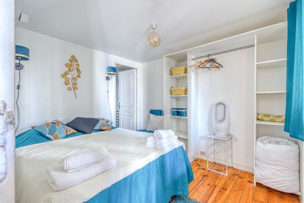 A bedroom with a bed, a bedside table, a heater, a wardrobe, and a hanging rack.
