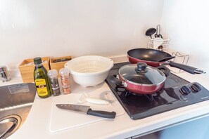 Een koelkast, een magnetron, een kookplaat, kookgerei, borden en bestek